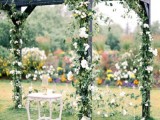 an organic wedding arch decorated with greenery and white blooms is a cool rustic idea to try