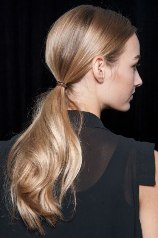 A low ponytail with a sleek top and a wavy pony is a stylish and fast to realize idea