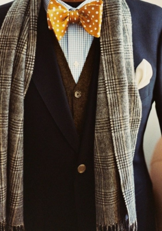 a beautiful and elegant groom's outfit with a blue checked shirt, a brown cardigan, a navy blazer, a mustard polka dot bow tie and a grey checked scarf