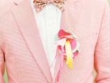 a colorful groom’s outfit with a white shirt, a pink checked blazer and a super colorful floral print bow tie is great