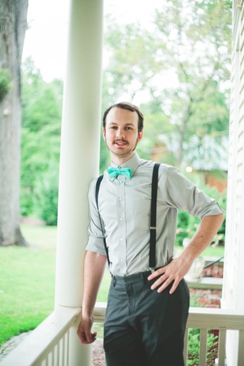 black pants, black suspenders, a grey shirt and a turquoise bow tie for a stylish groom's look with a touch of color