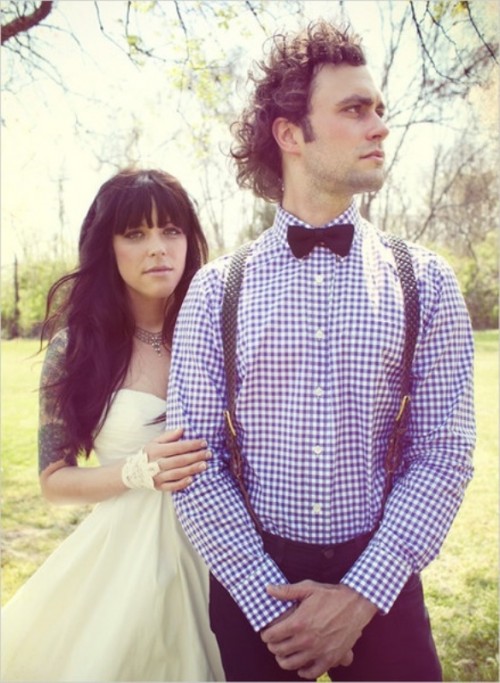 a blue plaid shirt, grey suspenders and a black bow tie plus black jeans for a rustic spring groom's look