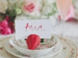 a chic wedding tablescape with pink floral arrangements, beautiful and chic floral porcelain and a strawberry to hold the card for a vintage summer wedding