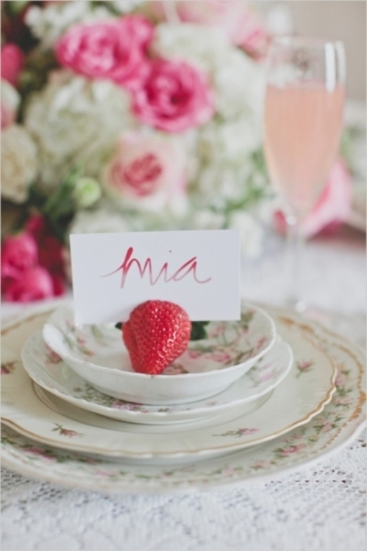 A chic wedding tablescape with pink floral arrangements, beautiful and chic floral porcelain and a strawberry to hold the card for a vintage summer wedding