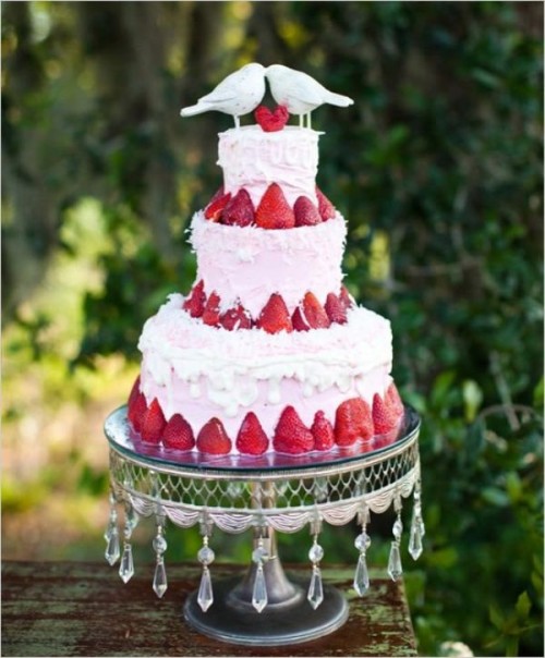 a fantastic pink buttercream wedding cake with frosting and strawberries, with a lovely bird wedding cake topper is amazing for a summer wedding