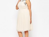 a neutral sleeveless knee A-line dress with black floral embroidery and a pleated skirt plus gold shoes is very feminine