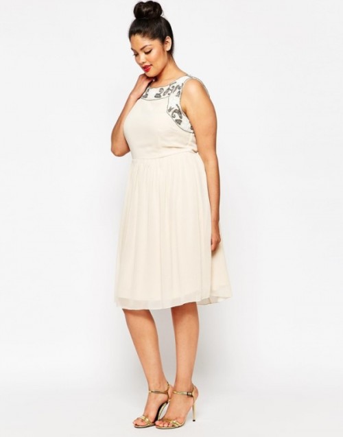 a neutral sleeveless knee A-line dress with black floral embroidery and a pleated skirt plus gold shoes is very feminine