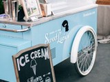 a modern ice cream trolley in blue and white, with a chlkboard sign and an umbrella is a lovely idea for a modern wedding