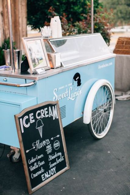 a modern ice cream trolley in blue and white, with a chlkboard sign and an umbrella is a lovely idea for a modern wedding
