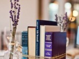 a bundled books centerpiece and some candles plus lavender in bottles around make up simple and stylish decor