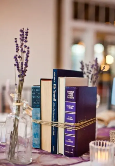 a bundled books centerpiece and some candles plus lavender in bottles around make up simple and stylish decor