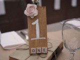 vintage books with a tie, a plywood table number and a pink bloom for a book lover wedding