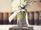 a stack of vintage books with a floral arrangement in a jar is a chic idea to try