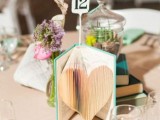 a whimsy book wedding centerpiece of a single book with pages cut to form a heart and a table number