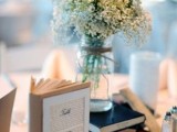 some books and a white floral arrangement in a jar is a proper idea to decorate a rustic wedding