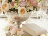 some books and a large bowl with a lush blush and iivory florla arrangement for a vintage-inspired wedding
