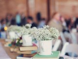 a stack of books with a cup filled with baby’s breath is a cool idea for a casual wedding with a retro twist