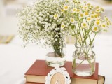 a book wedding centerpiece with a frame table number and clear vases with chamomiles and baby’s breath