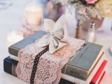 a vintage book wedding centerpiece – s stack wrapped with lace and with a paper bloom
