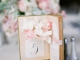 a book plus an open book with a table number and some fresh blooms attached inside for a romantic touch