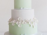 a fresh spring-like mint green and white wedding cake with ribbons, sugar flowers on the sides and on top