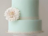 a chic mint green wedding cake with white lace ribbons, a single white bloom on a stylish and refined stand