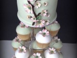 a whimsy mint green wedding cake decorated with pink sugar blooms and matching cupcakes for a chic dessert table