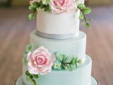 an ombre mint green wedding cake with shiny ribbons and sugar greenery and blooms and two pink flowers