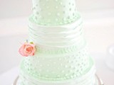 a whimsy mint green wedding cake decorated with ruffles and polka dots and fresh pink blooms here and there