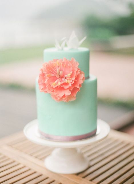 a stylish mint green wedding cake with a copper touch, white shards on top and a coral sugar bloom
