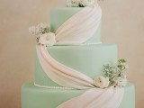 a formal mint green wedding cake decorated with edible white ribbon and fresh blooms and greenery