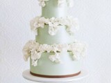 a luxurious mint green wedding cake topped with lots of white sugar blooms