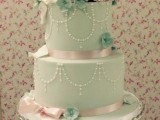 a mint green wedding cake with shiny ribbon, edible beads and lots of sugar blooms in pink and green