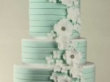 a striped mint green wedding cake decorated with white sugar blooms and beads all over