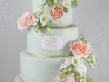 a romantic mint green wedding cake with shiny ribbon, a monogram and fresh peachy and white blooms and greenery