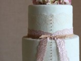 a mint green wedding cake decorated with white and pink lace and fresh pink hydrangeas on top
