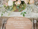 a simple and cute round kraft paper menu with white calligraphy is a cool and chic idea for a wedding tablescape with a rustic feel