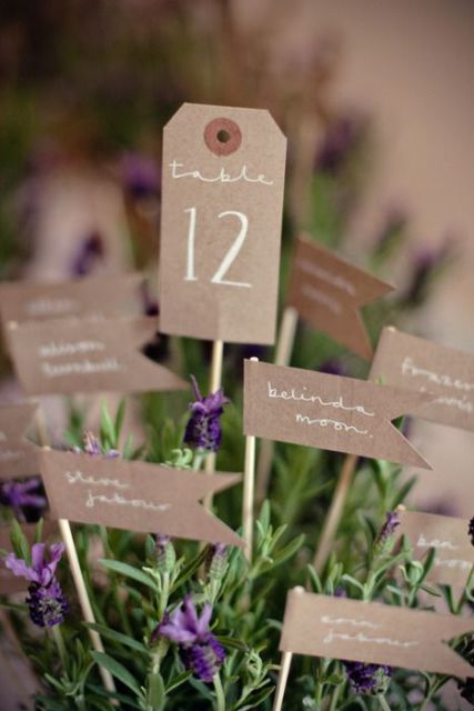 a potted bloom with a kraft paper table number and kraft paper names with calligraphy is a unique alternative to a wedding seating chart