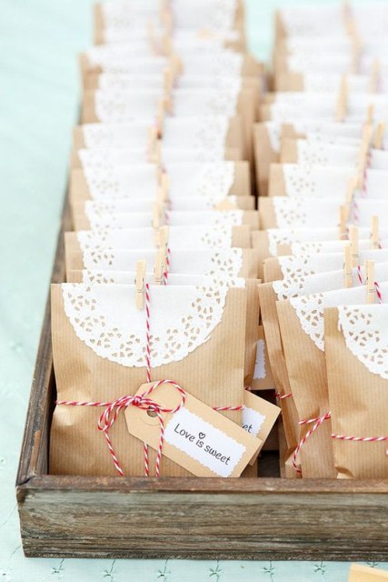 kraft paper bags topped with doilies, with twine and tags are great to pack your wedding favors, they look nice and are budget friendly
