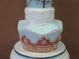 a beautiful blue and white winter wedding cake with a ball on top decorated with gingerbread cookies – house-shaped ones and people-shaped ones on top