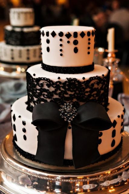 a bold and playful black and white wedding cake with black lace, embellishments, a black bow with an embellished brooch is a chic solution for a black and white wedding