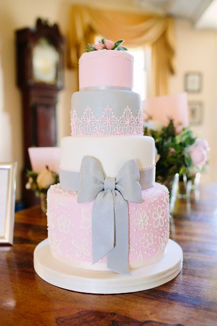 a white, grey and pink wedding cake with patterned tiers, a grey ribbon bow and some pink blooms on top is a gorgeous idea for a summer or spring wedding
