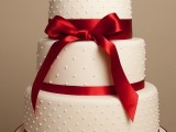 a white polka dot wedding cake accented with red silk ribbons and a ribbon bow is a stylish idea with much contrast is fantastic for a bold wedding