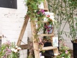a ladder wedding decoration with lots of greenery and blooms, with some artworks and prints