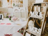 a wedding seating chart of a wooden ladder, some letters, a cage, a bunting, a seatign plan and some blooms