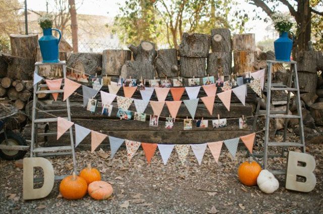 A rustic wedding decoration of two ladders, colorful buntings, family photos and bright pumpkins for a fall feel