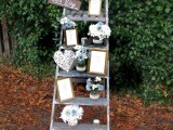 a cute rustic wedding decoration of a ladder, pastel and neutral blooms, a woven heart, some artworks and a sign