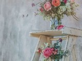 a vintage rustic wedding decoration of a whitewashed ladder and bright florals and greenery in jars