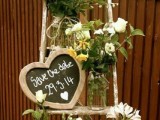 a rustic save the date decoration of a ladder, white blooms and greenery and a chalkboard heart-shaped sign