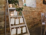 a rustic wedding seating chart made of a ladder, pastel blooms, candles, seating plans is romantic
